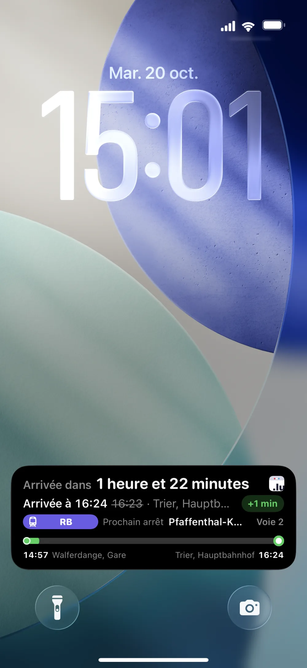 Écran verrouillé d'iPhone affichant le bandeau de trajet : ligne RE vers Trier Süd, retard de 1 minute, voie 2, départ dans 5 minutes, 19h05 au lieu de 19h04